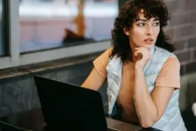 Designer thinking at a laptop while evaluating the potential of a new creative business idea before launch.