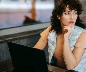 Designer thinking at a laptop while evaluating the potential of a new creative business idea before launch.