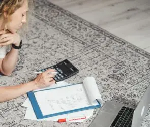 Freelance designer calculating project finances and monthly expenses while working from home.